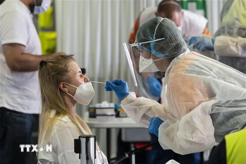 Nhân viên y tế lấy mẫu xét nghiệm COVID-19 cho người dân tại London (Ảnh: AFP/TTXVN)