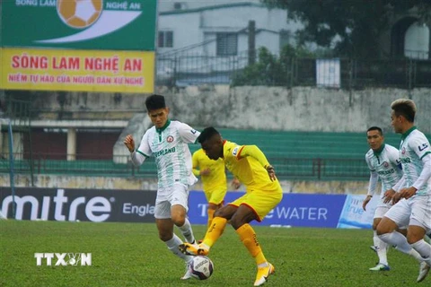 Một pha xử lý bóng của cầu thủ Sông Lam Nghệ An (áo vàng) trước các cầu thủ Bình Định. (Ảnh: Tá Chuyên - TTXVN)