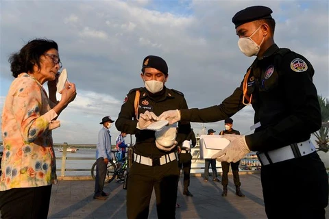 Cảnh sát phát khẩu trang miễn phí cho người dân tại Phnom Penh, Campuchia. (Ảnh: AFP/TTXVN)