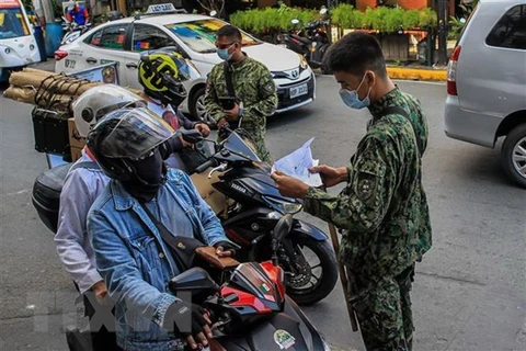 Cảnh sát làm nhiệm vụ tại một chốt kiểm tra y tế nhằm ngăn chặn sự lây lan của COVID-19 ở Manila, Philippines. (Ảnh: THX/TTXVN) 