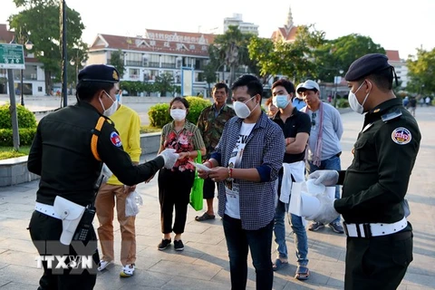 Cảnh sát phát khẩu trang cho người dân để phòng dịch COVID-19 tại Phnom Penh, Campuchia. (Ảnh: AFP/TTXVN) 