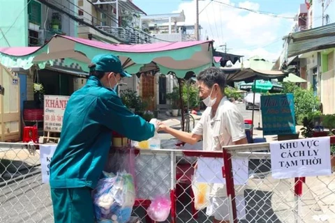 Phát thực phẩm, nhu yếu phẩm cho người dân trong khu vực bị phong tỏa tại con hẻm trên đường Đoàn Phú Tứ, phường An Lạc A, TP.Hồ Chí Minh. (Ảnh: TTXVN phát)