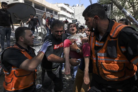 Nhân viên y tế giải cứu một em nhỏ khỏi toà nhà bị sập sau vụ oanh tạc của máy bay Israel xuống quận Rimal, thành phố Gaza ngày 16/5/2021. (Ảnh: AFP/TTXVN)