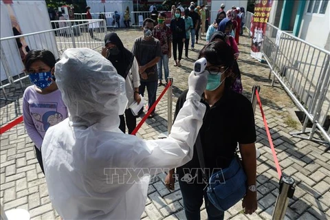 Nhân viên y tế kiểm tra thân nhiệt người dân ở Nam Tangerang, Indonesia nhằm ngăn dịch COVID-19 lây lan. (Ảnh: THX/TTXVN)