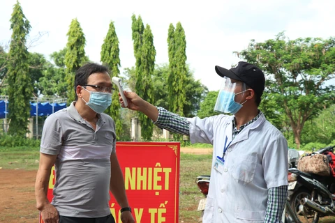 Đo thân nhiệt cho người vào tỉnh Đắk Lắk tại chốt kiểm soát phòng, chống dịch COVID-19 trên Quốc lộ 14. (Ảnh: Tuấn Anh – TTXVN)