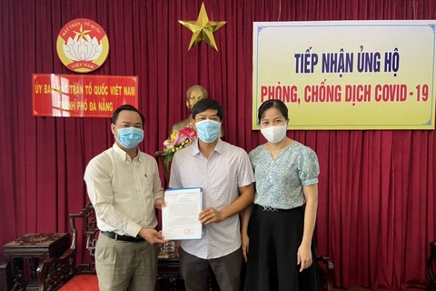 Anh Đỗ Đình Tuyển (đứng giữa) nhận thư cảm ơn của Ủy ban MTTQ Việt Nam thành phố Đà Nẵng sau khi ủng hộ 100 triệu cho Quỹ vaccine phòng, chống COVID-19. (Ảnh: Quốc Dũng - TTXVN)