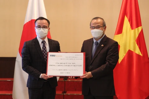 Ông Nguyễn Văn Hưng, Giám đốc Công ty Cổ phần JIT, trao tượng trưng tiền ủng hộ Quỹ vaccine cho Đại sứ Vũ Hồng Nam. (Ảnh: Đào Thanh Tùng/TTXVN)