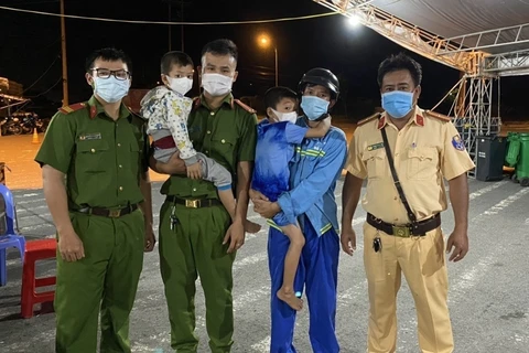 Hai bé trai được cán bộ Công an chốt kiểm soát dịch COVID-19 phường Tân Phú, quận Cái Răng, TP Cần Thơ bàn giao cho người thân. (Ảnh: TTXVN phát)