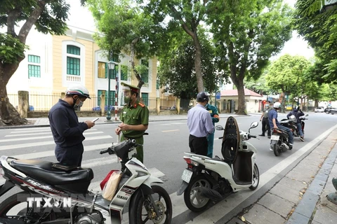 Công an đóng vai trò nòng cốt, phối hợp cùng lực lượng bảo vệ dân phố trong việc kiểm tra, nhắc nhở người dân chấp hành nghiêm quy định về phòng, chống dịch. (Ảnh: Minh Quyết/TTXVN)