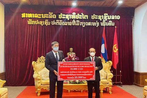 Đồng chí Nguyễn Đăng Hùng, Tổng Lãnh sự quán Việt Nam tại Luang Prabang (bên trái), trao tượng trưng quà của Đảng bộ, Chính quyền và Nhân dân Thủ đô Hà Nội tặng tỉnh Luang Prabang. (Ảnh: Tổng Lãnh sự quán Việt Nam tại Luang Prabang cung cấp)