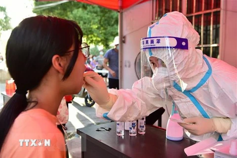 Nhân viên y tế lấy mẫu xét nghiệm COVID-19 cho người dân tại Trung Quốc. (Ảnh: THX/TTXVN) 