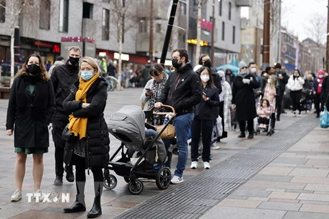 Người dân xếp hàng chờ lấy mẫu xét nghiệm COVID-19 tại London, Anh ngày 18/12/2021. (Ảnh: AFP/TTXVN)