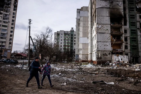 Người dân bên ngoài một khu nhà bị hư hại trong chiến sự tại Ukraine, hôm 4/3. (Ảnh: AFP.)