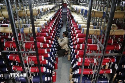 Công nhân kiểm tra các ống sợi trên máy dệt thảm tại một nhà máy ở ngoại ô Jammu, Ấn Độ. (Ảnh: AFP/TTXVN) 