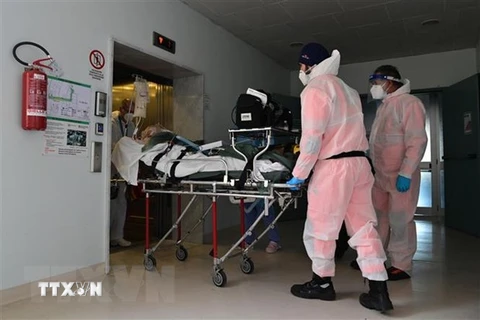 Nhân viên y tế chuyển bệnh nhân COVID-19 vào bệnh viện ở Cremona, Italy. (Ảnh: AFP/TTXVN) 
