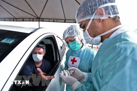 Nhân viên y tế xét nghiệm nhanh COVID-19 cho người dân tại một bãi đỗ xe ở Brasilia, Brazil. (Nguồn: AFP/TTXVN)