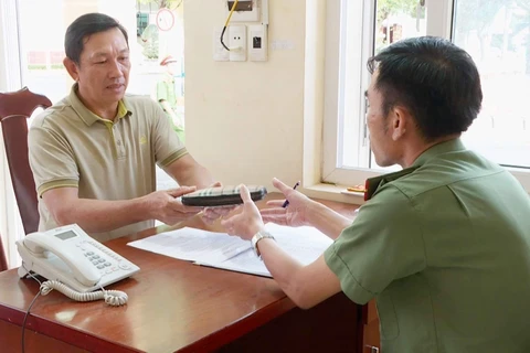 Ông Nguyễn Hữu Hùng mang chiếc ví nhặt được đến phòng Trực ban của Công an tỉnh Đắk Lắk trình báo, giao nộp. (Ảnh: TTXVN phát)