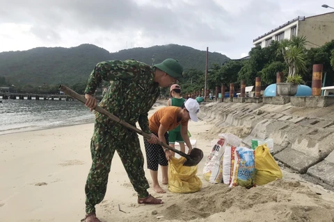 Cán bộ chiến sỹ Đồn biên phòng Cù Lao Chàm, bộ đội biên phòng Quảng Nam giúp đỡ người dân gia cố mái nhà bằng bao tải cát. (Ảnh: Đoàn Hữu Trung/TTXVN)