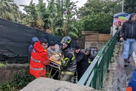 Nhân viên cứu hỏa sơ tán người dân sau trận lở đất trên đảo Ischia, ngày 26/11/2022. (Ảnh: AFP/TTXVN)