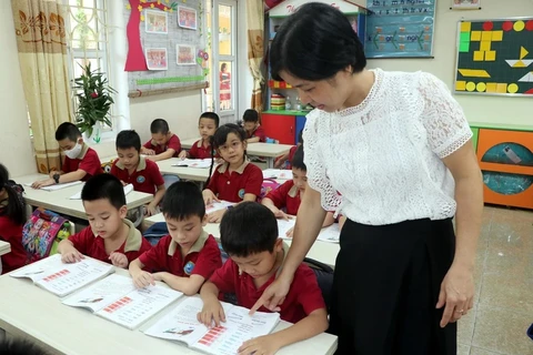 Giáo viên hướng dẫn học sinh làm bài tập. (Ảnh: Nguyễn Lành/TTXVN)