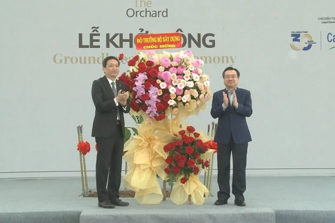 Bộ trưởng Bộ Xây dựng Nguyễn Thanh Nghị (phải) tặng hoa chúc mừng. (Ảnh: Huyền Trang/TTXVN)