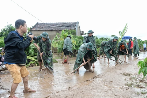 Phóng viên Danh Lam, Cơ quan thường trú Bắc Giang, tác nghiệp tại hiện trường khắc phục hậu quả mưa lũ tại thôn Khả Lã, xã Tân Lập, Lục Ngạn, Bắc Giang. (Ảnh: TTXVN)