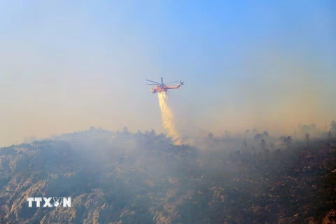 Trực thăng cứu hỏa tham gia dập đám cháy rừng gần ở Hy Lạp. (Ảnh: Reuters/TTXVN)