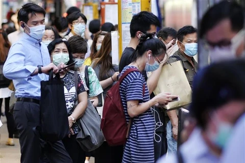 Trong ảnh: Người dân đeo khẩu trang phòng lây nhiễm COVID-19 khi chờ xe buýt tại Hong Kong, Trung Quốc. (Ảnh: THX/TTXVN)