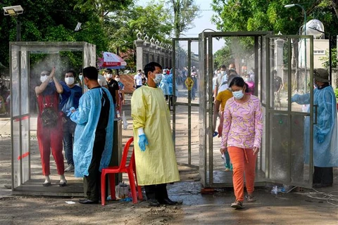 Người dân được khử khuẩn trước khi vào tiêm chủng vaccine ngừa COVID-19 tại Phnom Penh, Campuchia, ngày 20/5/2021. (Ảnh: AFP/TTXVN)