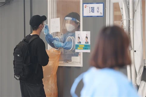 Nhân viên y tế lấy mẫu xét nghiệm COVID-19 cho người dân tại Seoul, Hàn Quốc. (Ảnh: YONHAP/TTXVN)