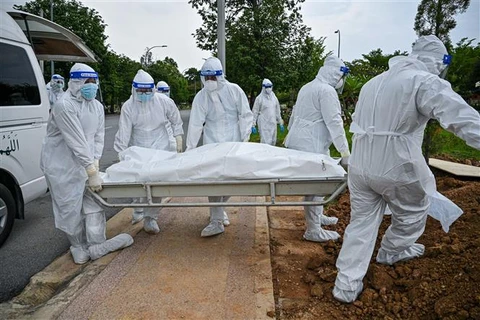 Các tình nguyện viên chôn cất thi thể bệnh nhân COVID-19 tại Kuala Lumpur (Malaysia), ngày 15/6/2021. (Ảnh: AFP/TTXVN)