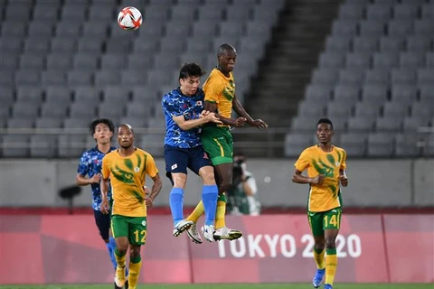 Pha tranh bóng bổng giữa các cầu thủ Nhật Bản và Nam Phi trong trận đấu tại Olympic Tokyo 2020 trên sân Saitama, ngày 22/7/2021. (Ảnh: AFP/TTXVN)