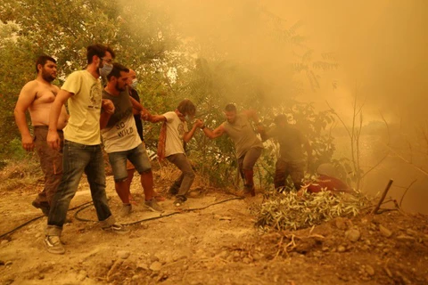 Người dân vượt một con dốc khi đám cháy rừng bùng lên ở làng Gouves, trên đảo Evia (Hy Lạp), ngày 8/8/2021. (Nguồn: reuters.com)