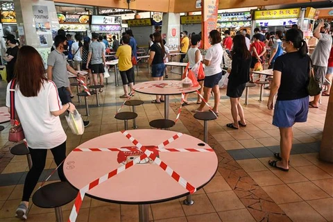 Người dân xếp hàng mua đồ ăn mang về để phòng lây nhiễm COVID-19 tại Singapore. (Ảnh: AFP/TTXVN)