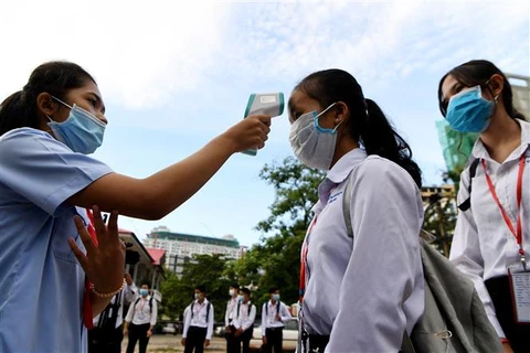 Kiểm tra thân nhiệt phòng lây nhiễm COVID-19 trong lớp học tại Phnom Penh (Campuchia). (Ảnh: AFP/TTXVN)