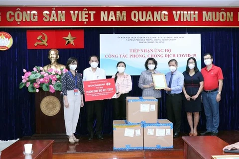 Bà Tô Thị Bích Châu, Chủ tịch Ủy ban Mặt trận Tổ quốc Việt Nam Thành phố Hồ Chí Minh (giữa) trao thư cảm ơn cho đại diện ngân hàng Techcombank đã ủng hộ 2 triệu bộ xét nghiệm COVID-19. (Ảnh: Xuân Khu/TTXVN)