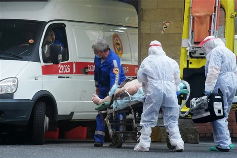 Nhân viên y tế chuyển bệnh nhân nhiễm COVID-19 tới bệnh viện ở Saint Petersburg (Nga). (Ảnh: AFP/TTXVN)