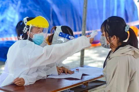 Nhân viên y tế đo thân nhiệt cho người dân trước khi tiêm vaccine, tại Đà Nẵng. (Ảnh: Văn Dũng/TTXVN)
