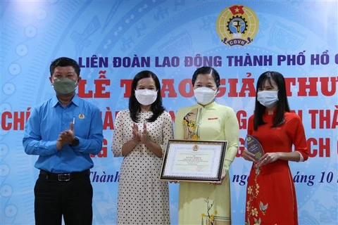 Ông Trần Đoàn Trung, Phó Chủ tịch Thường trực Liên đoàn Lao động Thành phố Hồ Chí Minh trao giải thưởng cho các phóng viên, biên tập viên đoạt giải. (Ảnh: Thanh Vũ/TTXVN)