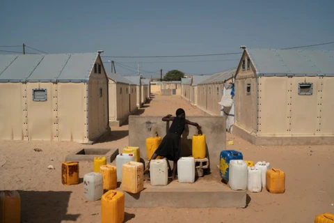 Một bé gái lấy nước vào các can nhựa tại một trại dành cho những người mất nhà cửa ven biển do bị xói mòn ở Saint Louis (Senegal), hôm 4/11, khi COP26 đang diễn ra ở Scotland. (Nguồn: washingtonpost.com)