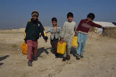 Trẻ em đi lấy nước tại trại tị nạn ở Mazar-i-Sharif, tỉnh Balkh (Afghanistan), ngày 20/11/2021. (Ảnh: THX/TTXVN)