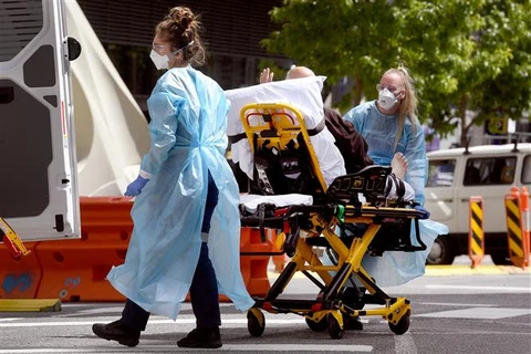 Nhân viên y tế chuyển bệnh nhân COVID-19 tại bệnh viện ở Melbourne (Australia). (Ảnh: AFP/TTXVN)