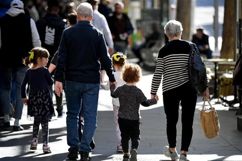 Trẻ em đi chơi cùng ông bà trên một đường phố ở Melbourne (Australia), ngày 28/6/2021. (Ảnh: AFP/TTXVN)