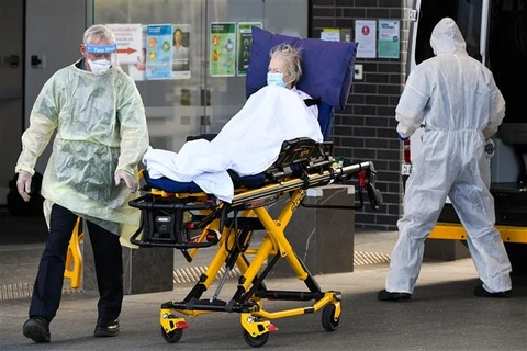 Nhân viên y tế chuyển bệnh nhân COVID-19 tại Melbourne (Australia). (Ảnh: AFP/TTXVN)