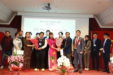 Đại diện Tổng lãnh sự quán Việt Nam tại Fukuoka tặng hoa cho Chủ tịch Hội người Việt Nam tại Kitakyushu. (Ảnh: TTXVN)