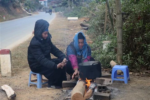 Người dân sinh sống dưới chân đèo Pha Đin, cạnh quốc lộ 6 đốt lửa sưởi ấm, chống chọi với giá lạnh. (Ảnh: Xuân Tiến/TTXVN)