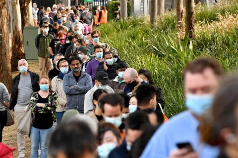 Người dân xếp hàng bên ngoài một điểm tiêm vaccine phòng COVID-19 tại Sydney (Australia). (Ảnh: AFP/TTXVN)