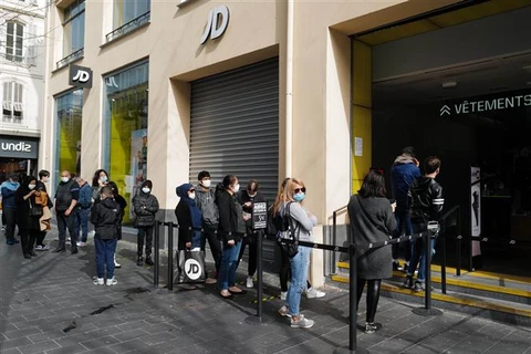 Người dân đeo khẩu trang phòng lây nhiễm COVID-19 khi xếp hàng bên ngoài một cửa hiệu ở Nice (Pháp). (Ảnh: THX/TTXVN)