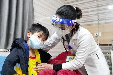 Bác sỹ Khoa Nhi, Bệnh viện đa khoa Hùng Vương thăm khám cho cháu Phạm Quốc C. (Ảnh: TTXVN)