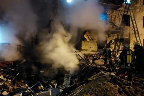 Lính cứu hoả dập lửa toà nhà chung cư bị phá hủy ở Koshytsa, ngoại ô thủ đô Kiev, trong chiến dịch quân sự của Nga tại Ukraine, ngày 25/2/2022. (Ảnh: AFP/TTXVN)